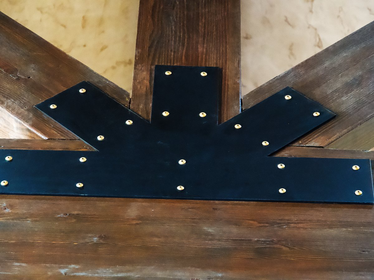 Blackened steel truss plate detail against timber